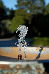 Water Splash from Drinking Fountain on a Sunny Day &ndash; Blurred Background. Dynamic Splash in Public Drinking Fountain under Bright Sun with Bokeh Background
