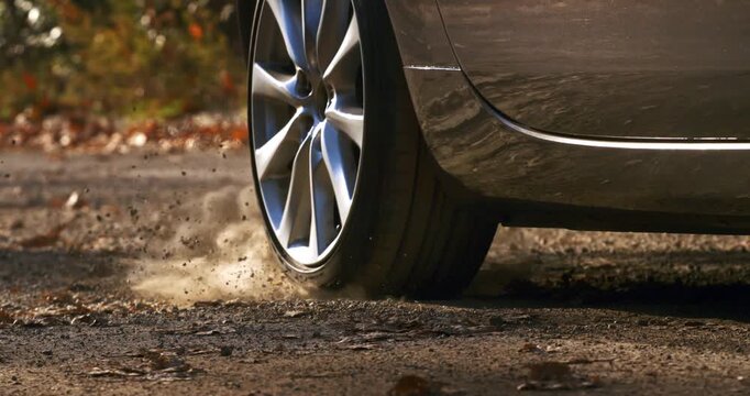 Slow Motion Close Up Of Car Wheel Spinning With Dust And Smoke. Power And Motion Concept