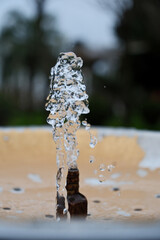 Water Splash from Drinking Fountain in Park &ndash; Blurred Background. Fresh Water Droplets from Resort Drinking Fountain, Shallow Depth of Field