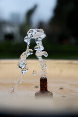 Water Splash from Drinking Fountain in Park &ndash; Blurred Background. Fresh Water Droplets from Resort Drinking Fountain, Shallow Depth of Field