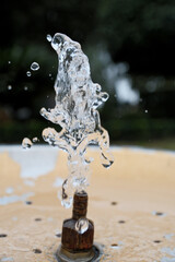 Water Splash from Drinking Fountain in Park &ndash; Blurred Background. Fresh Water Droplets from Resort Drinking Fountain, Shallow Depth of Field