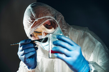 Forensic investigator dusting fingerprint on glass tumbler  using powder and brush during evidence...