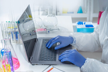 Experienced professor recording experimental data on a laptop while working in a laboratory....