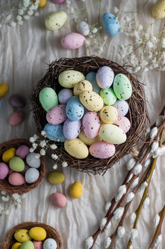 Easter mini decorative eegs in a nest with willow twigs, bright background
