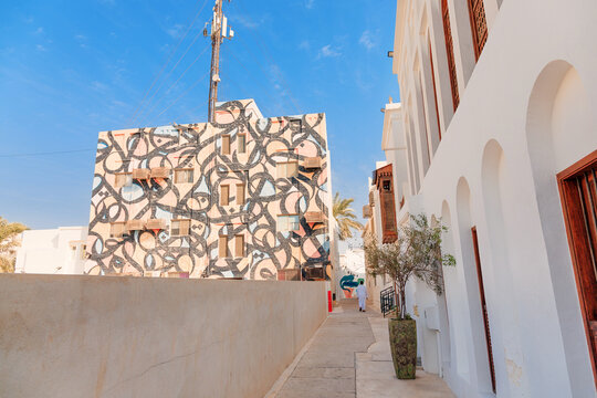 3 December 2025, Bahrain, Manama: Historic Muharraq district alleyway with a modern building facade featuring Arabic calligraphy mural