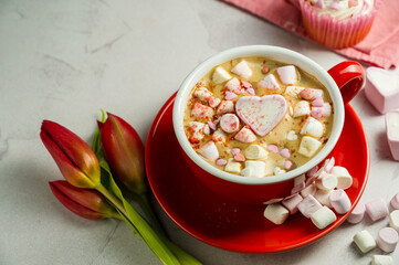 Valentine's Day background. Red cup of coffee with heart shaped marshmallows and ret tulips