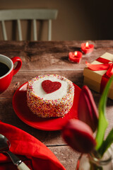 Valentine's Day background. Cake with red heart, candles, gift box and cup of coffee on table. Love celebration
