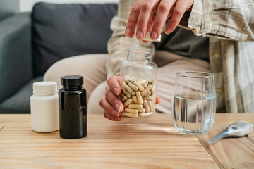 Woman pouring a pile of pills, capsules from bottle in hand. Prescription medication, treatment sickness concept
