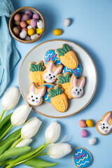 Easter spring holiday background with easter cookies in a plate: bunny, carrot and egg with white tulips