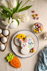 Easter festive background. Colourful easter cookies bunny, egg, chick and carrot. White spring tulips bouquet.
