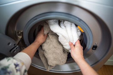 Washing machine at home. Smart appliances. Woman loading the washing machine with towels. Daily chores. Cleaning laundry