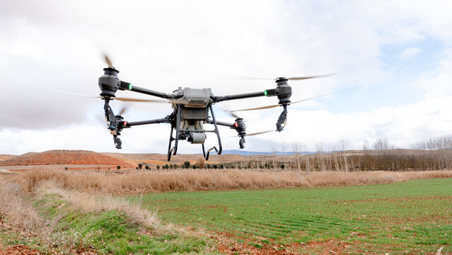 Agricultural drone spraying liquid fertilizer over wheat field