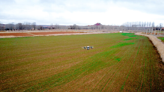Agricultural drone spreading solid fertilizer over field