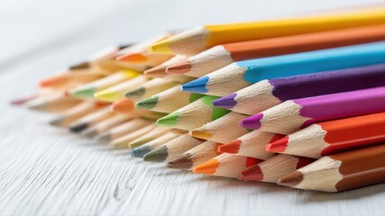 Naklejka premium Arrangement of vibrant colored pencils on a white wooden surface creates a striking visual aesthetic