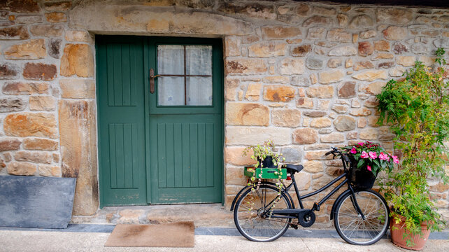 Vintage bicycle with flowers near rustic stone wall
