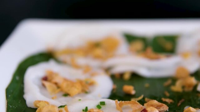 Rotation shot of many Idli or idly on banana leaf. Popular South Indian breakfast vegetarian food restaurant in Kerala Tamil Nadu India Sri Lanka. healthy steamed rice cakes .