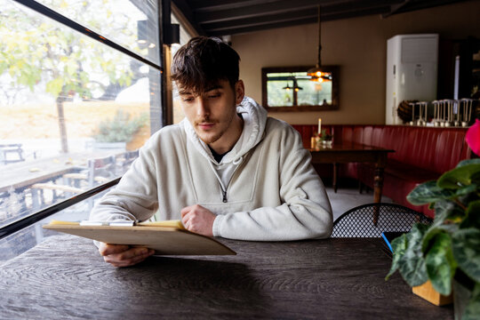 Young man reading menu in cozy cafe setting