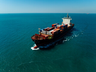 Aerial rear view of cargo ship sailing into blue ocean under clear sky © SHUTTER DIN