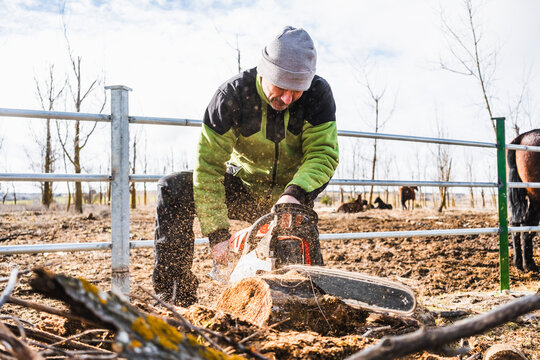 Man using chainsaw to cut wood outdoors