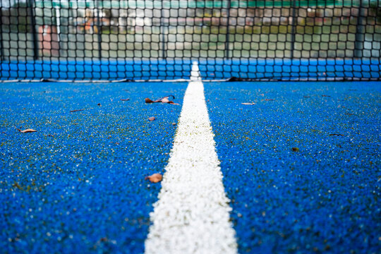 Close-up view of a blue padel court with net in focus