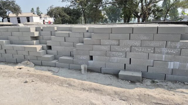 Professional RAW eye level wide shot of stacked eco-friendly grey concrete blocks in Bangladesh, 4K UHD 30fps.