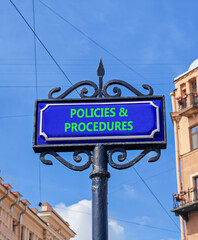 Fototapeta premium Policies and procedures symbol. Concept words Policies and procedures on beautiful big blue road sign. Beautiful blue sky and buildings background. Business policies procedures concept. Copy space