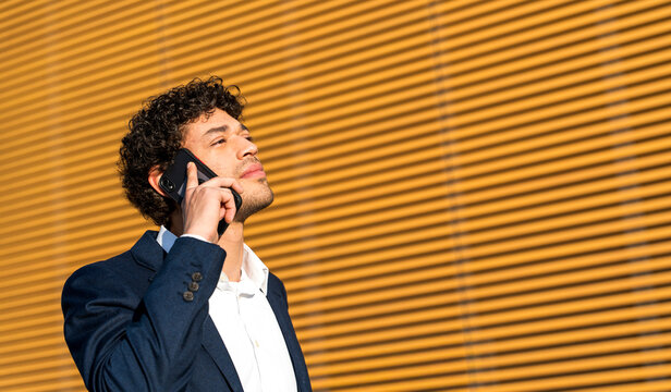 Businessman on a phone call outdoors in sunlight