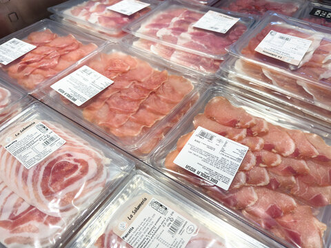 Venice, Italy - February 14, 2026: Assorted packaged deli meats displayed in a supermarket, including ham, bacon, and prosciutto in clear plastic containers