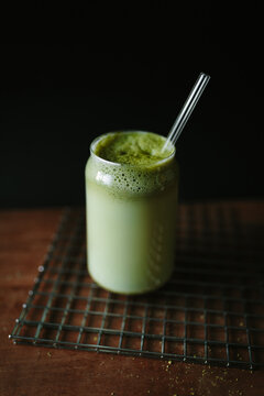 Matcha latte in a glass with a straw on a wire rack