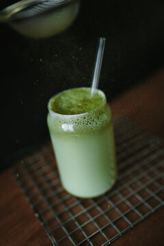 Matcha latte in a glass with a straw on a wire rack