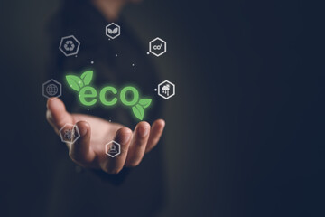 Obraz premium Hand holding glowing green eco text and environmental icons on dark background