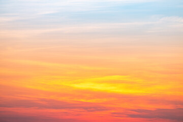 Naklejka premium Beautiful sunrise sky with vibrant gradient orange and gold colors and soft blue, Clear atmosphere with wispy clouds. Peaceful, perfect for background and copy space, High resolution images