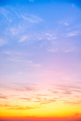 Obraz premium Beautiful sunrise sky with vibrant gradient orange and gold colors and soft blue, Clear atmosphere with wispy clouds. Peaceful, perfect for background and copy space, High resolution images Vertical