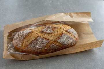 Whole rustic bread loaf in paper bag with transparent top