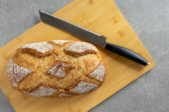 rustic sourdough bread with bread knife on cutting board top view
