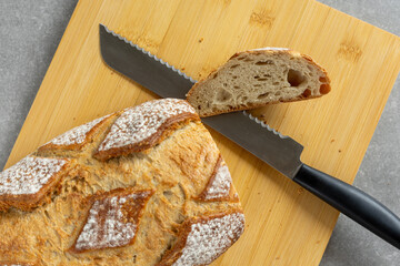 sliced rustic sourdough bread loaf with knife on cutting board