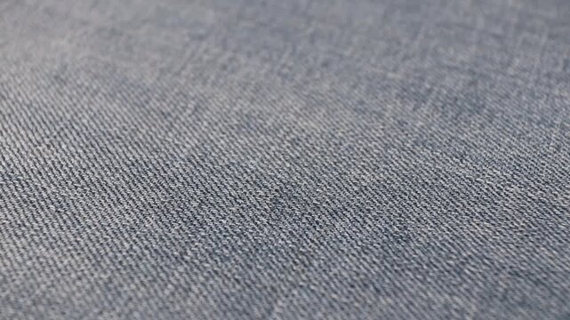 Static isometric view of worn blue denim fabric with shallow depth of field. Textured jeans material with soft blur and vintage distressed look for fashion or background design use.