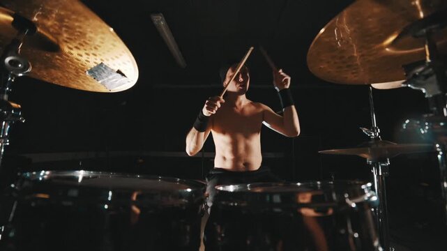 Shirtless rock drummer playing drums energetically
