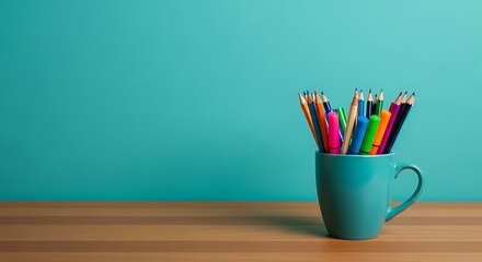Fototapeta premium Colorful pencils in a blue mug on a wooden table with a teal background bright and creative workspace