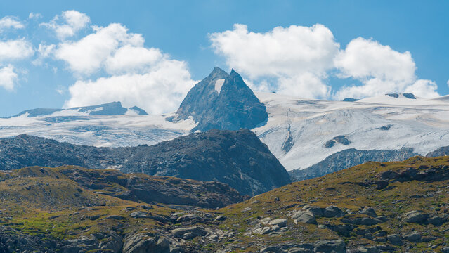 The summit of the mountain named "Rutor" with its wide glacier at both sides. Blue sky and white clouds on the background. Aosta Valley, Italy.