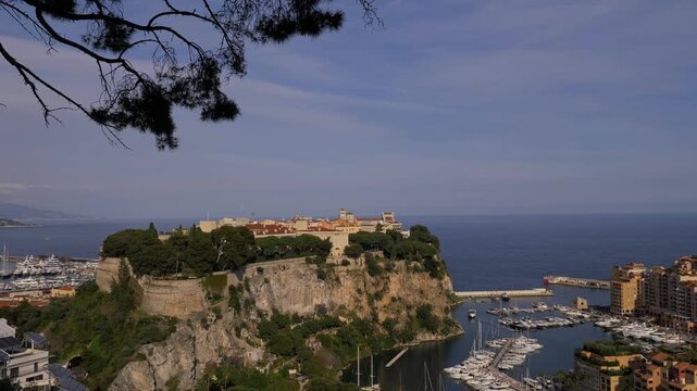 4K aerial-style view of Monaco Old Town (Le Rocher) perched on a dramatic cliff above the Mediterranean Sea. Historic fortress walls, marina with luxury yachts, and panoramic coastal Monaco 7 May 2019