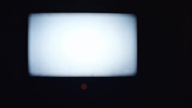 Glowing screen with blurry businessman silhouette in dark room for media concept