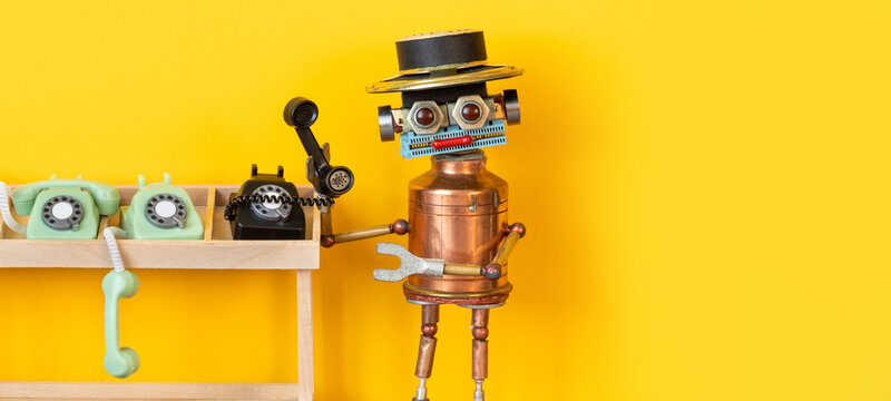Robot operator standing near wooden table with vintage telephones, holding black rotary phone receiver. Yellow background, copy space. Retro telephone exchange concept, communication poster