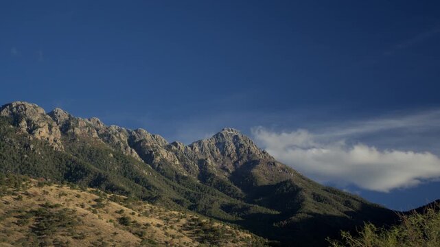 Time lapse of clouds skimming the top of a majestic mountain peak