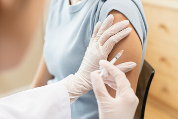 People getting a vaccination to prevent pandemic concept. Woman in medical face mask  receiving a dose of immunization coronavirus vaccine from a nurse at the medical center hospital © Pormezz
