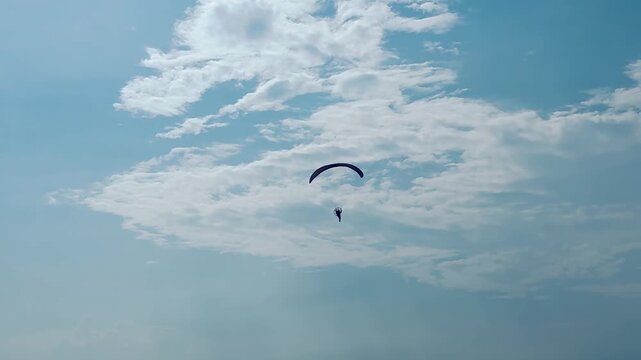 A motorized paraglider in the blue sky in the clouds