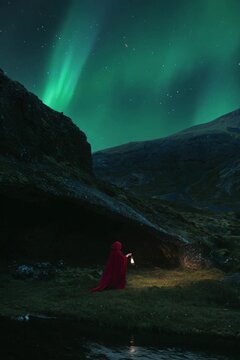 Person in a Red cape Walking under icelandic mountians