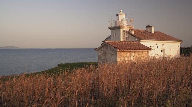 Lighthouse at Sunset by the Blue Sea Coast