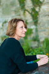 Obraz premium Mature woman with short brown hair looking thoughtfully to the side in an outdoor setting