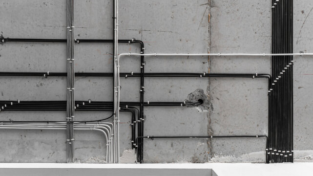 electrical installation work, cable laying. perfect wiring of cables on the ceiling. straight perpendicular lines. professional electrician, concrete slab, black and white cables, repair